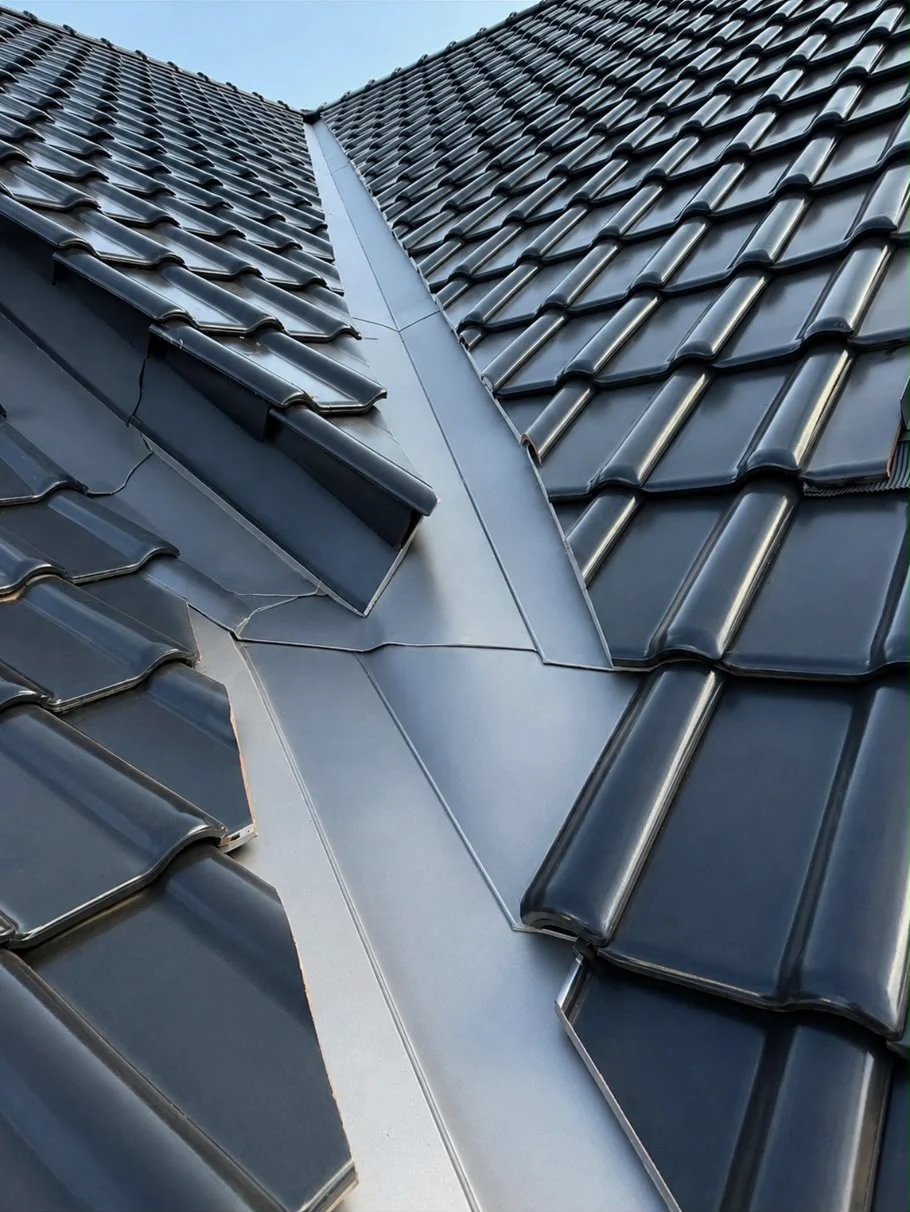 Neu ausgeführte Metallkehle zwischen zwei dunkel eingedeckten Dachflächen